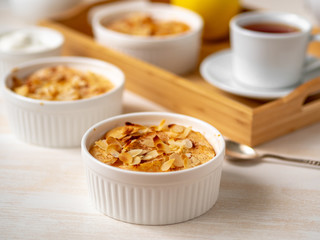 Cheesecake on white wooden table in kitchen. Delicate curd dessert with apples, almond flakes and cinnamon, side view