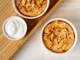 Cheesecake on white wooden table in kitchen. Delicate curd dessert with apples, almond flakes and cinnamon, top view, above