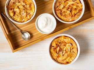 Cheesecake on white wooden table in kitchen. Delicate curd dessert with apples, almond flakes and cinnamon, top view, above