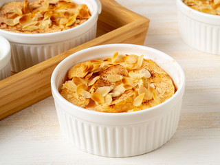 Cheesecake on white wooden table in kitchen. Delicate curd dessert with apples, almond flakes and cinnamon, side view