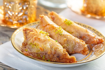 Traditional arabic dessert baklava with cashew, walnuts and cardamom with an eucalyptus branch on a wooden table