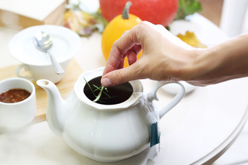 Herbata z rozmarynem. Kobieta zaparza aromatyczną herbatę w dzbanku - obrazy, fototapety, plakaty