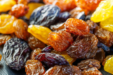 Assortment of Raisins, yellow, blue, black, golden raisin on dark background. Healthy snack, dietary product for good life. Food background and texture, Vega Food. Close-up image. Macro.