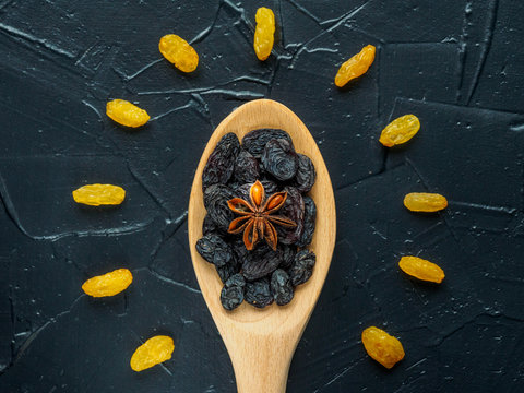 Blue Raisins in wooden spoon and anise on dark background.Composition in the form of sun or light bulb. symbol of idea or thought, raisins useful for brain. Healthy snack, Vega Food. Macro. Top view.