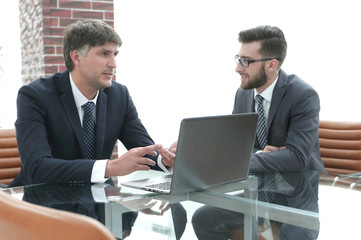 Two businessmen discussing tasks sitting at office table.