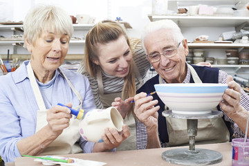 Senior Couple With Teacher In Pottery Class