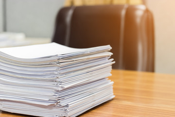 Stack of student's homework that assigned to students to be completed outside the class on teacher's desk. Document stacks on desk.