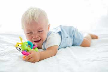 Toddler baby boy, playing with dummy, crying unhappy for the pacifier