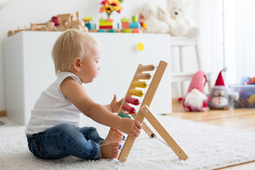 Cute little baby boy, playing with abacus at home