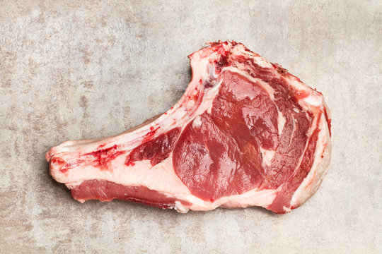 Chulet&oacute;n de carne vacuna sobre tabla r&uacute;stica gris. Vista superior.  Copy space. Copy space