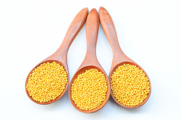 yellow mustard seeds in the wooden spoon on White background
