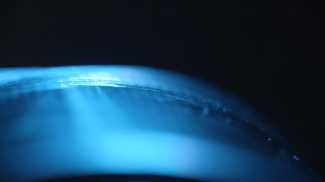 Mysterious rubber product close-up 4K. Panning shot over a shiny blue surface while focus pulling. Black background.