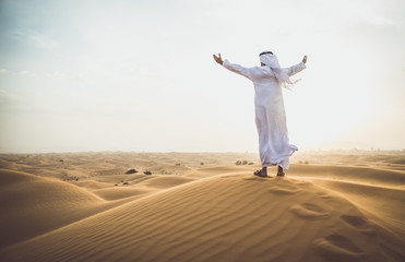 Fototapeta na wymiar Arabic man with traditional emirates clothes walking in the desert