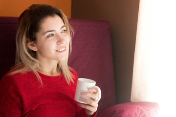 Mujer relajante en casa sosteniendo una taza de café