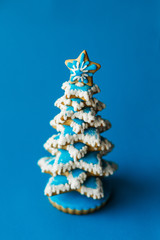 Blue chirstmas tree gingerbread cookie on blue background. Holidays food and decoration concept.