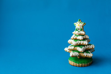 Blue chirstmas tree gingerbread cookie on blue background. Holidays food and decoration concept.