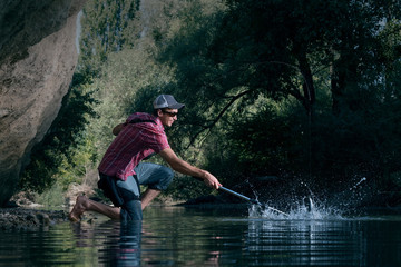 Fishing on the river. Fisherman catches a fish in forest. Man pulls a fish net.