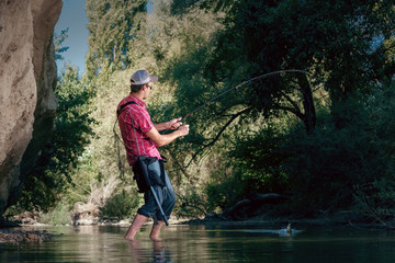 Fishing on the river. Man catches a fish on a lure Spinning. Fisherman with a fishing rod.