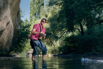 Fishing on the river. Professional sports fisherman catches a fish.