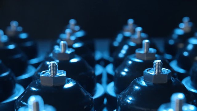 Slide over mass made rubber products 4K. Dolly slide zooming out over a number of rubber product on black background. Blue light shines from above.