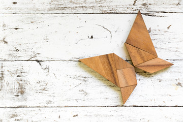 Tangram puzzle in butterfly shape on old white wood background