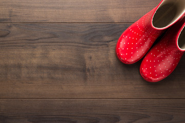 new red children's stylish gumboots on wooden floor with some copy space