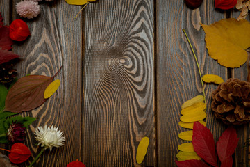 Autumn background. Bright orange berries, very flowers and leaves on a brown wood background. Background for autumn holidays and thanksgiving day.