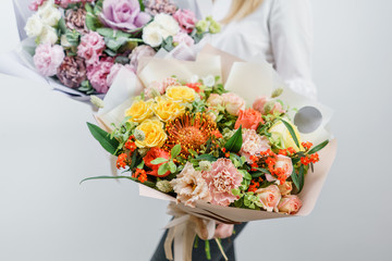two beautiful spring bouquet. Young girl holding a flowers arrangements with various of colors. white wall.