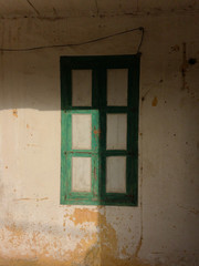 Vintage green wooden shutters with the light of the sun designing a rectangle on 1/3 of the shutters