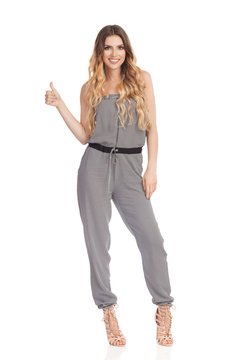 Smiling Young Woman In Jumpsuit Is Showing Thumb Up
