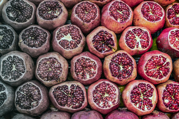 Sliced pomegranates in front of a juice stand.
