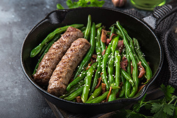 roasted green bean with bacon and sausages on cast iron pan