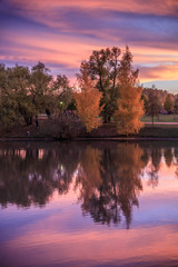 Obraz premium Autumn landscape. Fantastic dramatic colorful flaming sky, trees and reflections in the lake after sunset in the park. Autumn in Moscow parks, Russia.