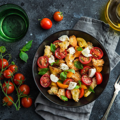 panzanella, traditional italian tomato, mozzarella and bread salad in black bowl