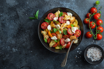 panzanella, traditional italian tomato, mozzarella and bread salad in black bowl