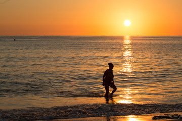 Obraz premium woman comes out of the sea in the rays of the rising sun