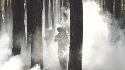 US Army soldiers patrol in a smoky forest