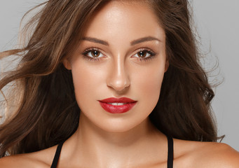 Beautiful brunette with red lips and long hair tanned skin with beauty eyes face closeup