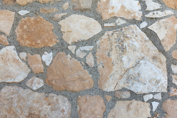 Texture of a stone wall.Different sizes of beige brown limestones with gray cement wide seams.Background concept.