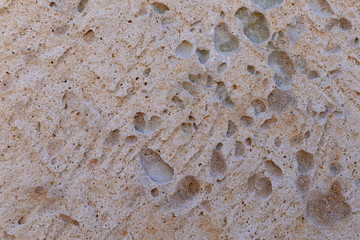 Background of beige textured limestone . Pocketed rough surface with dark inclusions