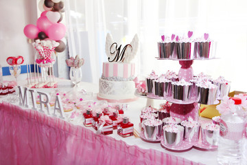 festive table decorations with cake, cupcakes, sweets and gifts in pink color