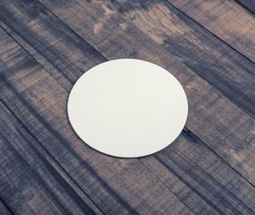 Blank white beer coaster on wooden background.