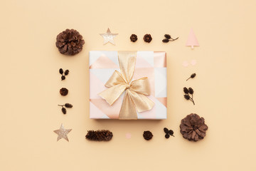 Beautiful christmas gift decorated with a ribbon bow isolated on beige background. Pink and gold wrapped xmas box composition.