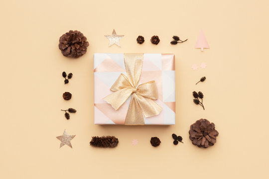 Beautiful Christmas Gift Decorated With A Ribbon Bow Isolated On Beige Background. Pink And Gold Wrapped Xmas Box Composition.