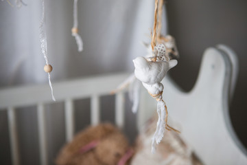 Small white bird toy hanging above the baby cot