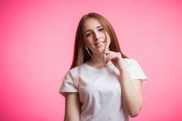 Portrait of happy ginger girl smiling looking at camera on a pink background with a copy space