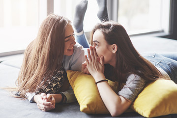 Two beautiful young twins sisters spending time together with pillows. Siblings having fun at home...