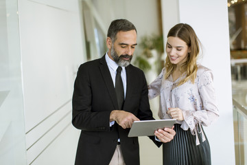 Young businesswoman and businessman look on digital tablet and discuss aout project