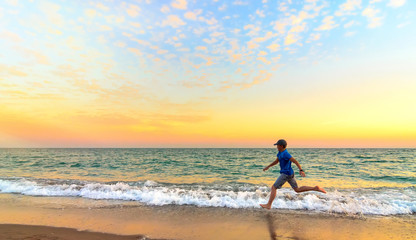 Fototapeta na wymiar Boy running along the beach at sunset