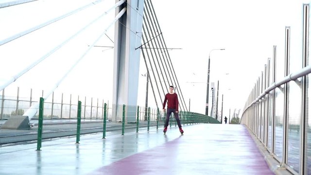 Young man in rollerblades doing spin in the city, super slow motion 
